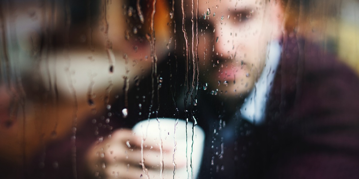 Rain running down a window with a person blurred in the background